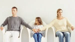 divorcing co-parents hold hand with child 